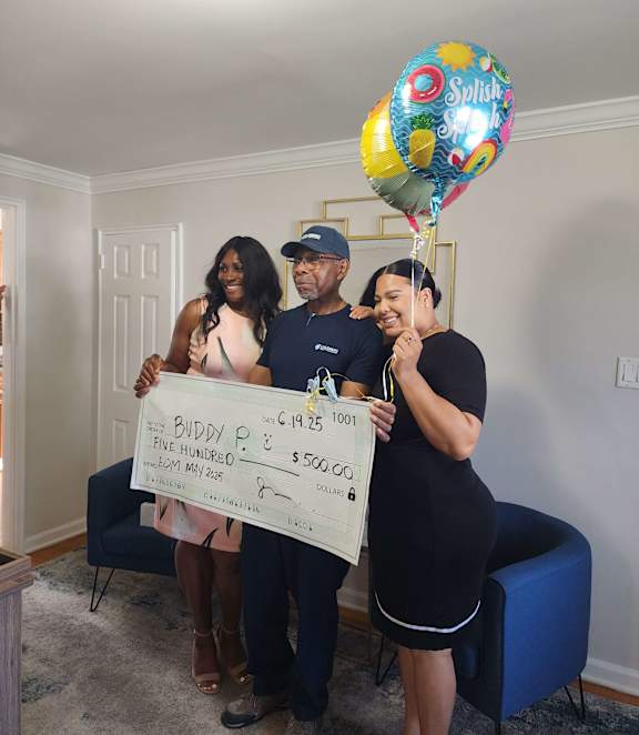 Three people holding a large check for $500.