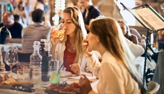 two women eating pizza at a restaurant at The Courtyards of Chanticleer, Virginia Beach, VA