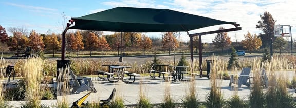 a patio with tables and chairs and a green canopy