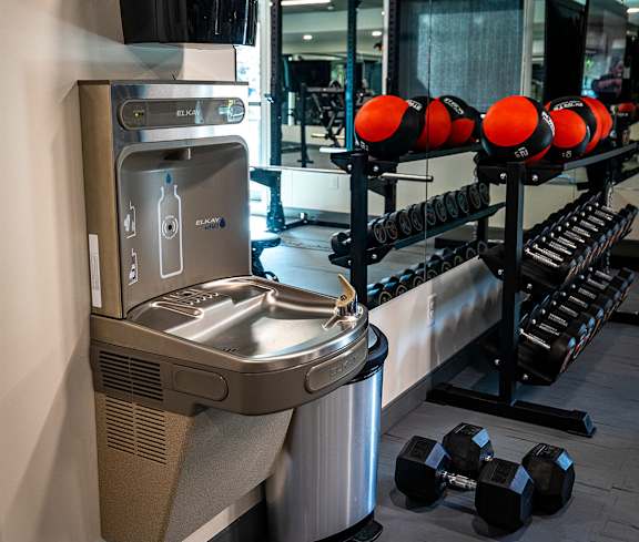 a fitness room with a water fountain and a rack of dumbbells