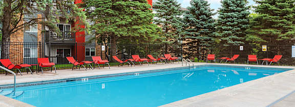A swimming pool surrounded by trees and chairs.