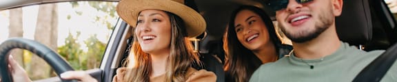 Three people are sitting in a car, with the woman driving and the two men in the back seat. at Bradley Square Apartments, South Carolina