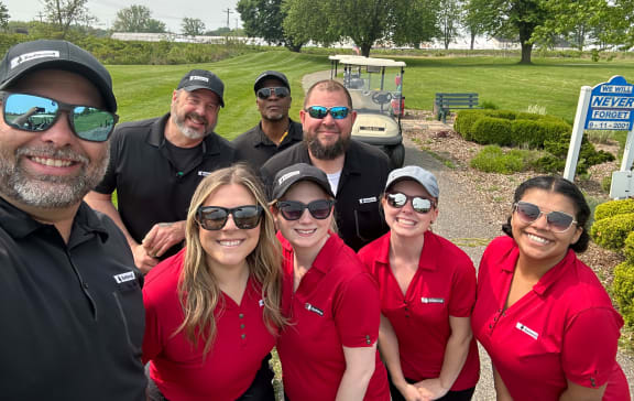 a group of people posing for a photo in front of a golf cart