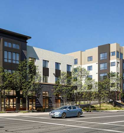 A modern apartment complex with cars parked in front.