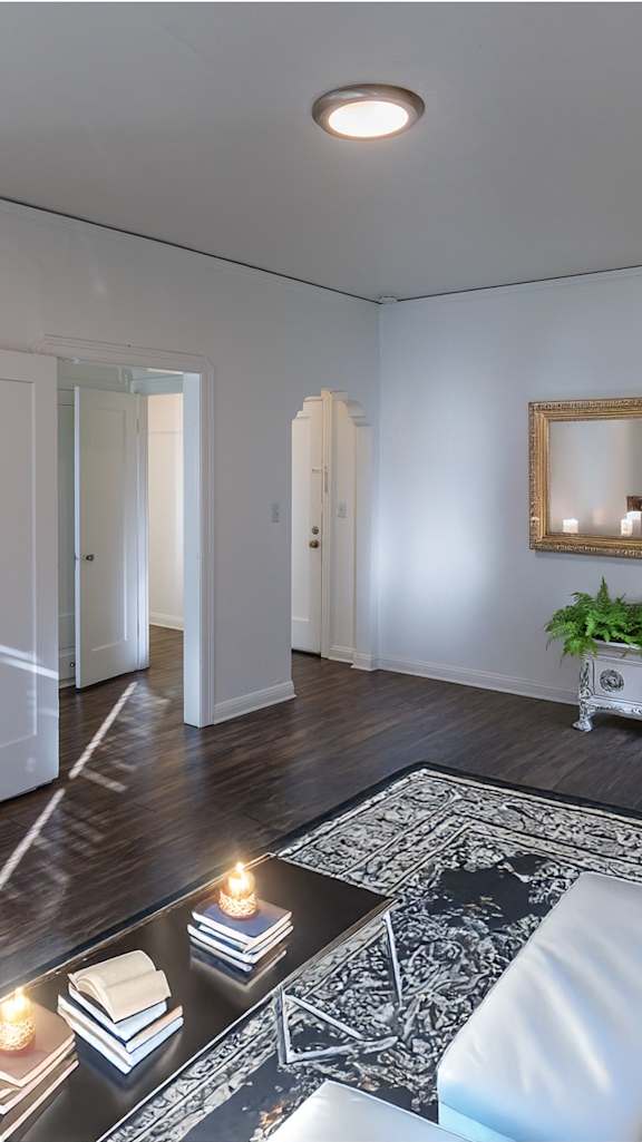 A living room with a white couch, a coffee table with candles, and a mirror on the wall.