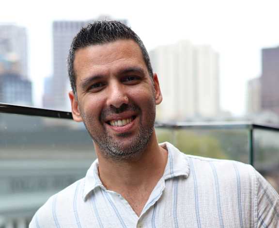 A man in a striped shirt is holding a phone to his ear.