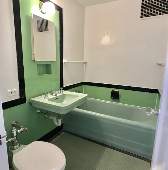 a green and white bathroom with a sink toilet and tub