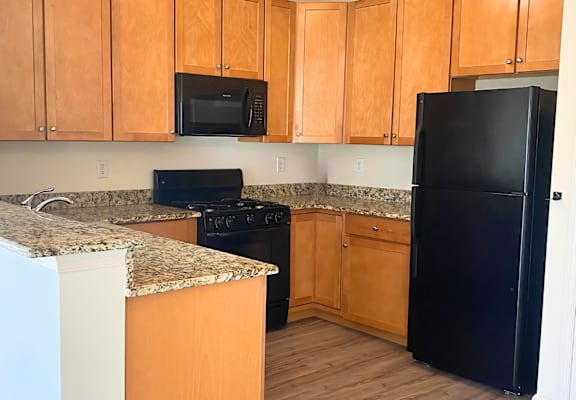 a kitchen with wooden cabinets and a black refrigerator