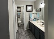 Thumbnail 22 of 27 - a bathroom with a toilet a sink and a mirror at The Lodge Apartments, Oklahoma, 74129
