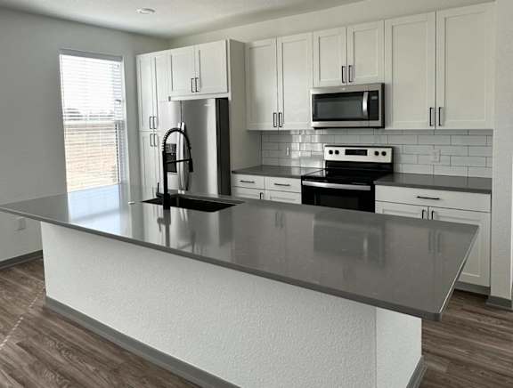 a kitchen with white cabinets and a black counter topat The BLVD at Wilson Crossings, Wyoming, MI
