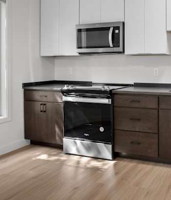 an empty kitchen with white cabinets and stainless steel appliances