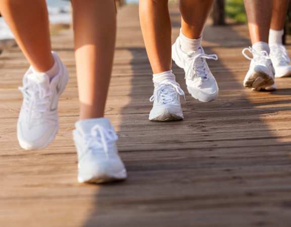 Three people are walking on a wooden path.