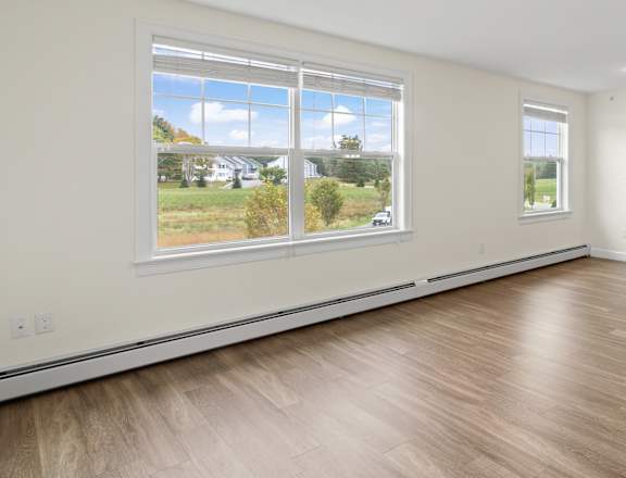 an empty kitchen and living room with wood flooring and a large window