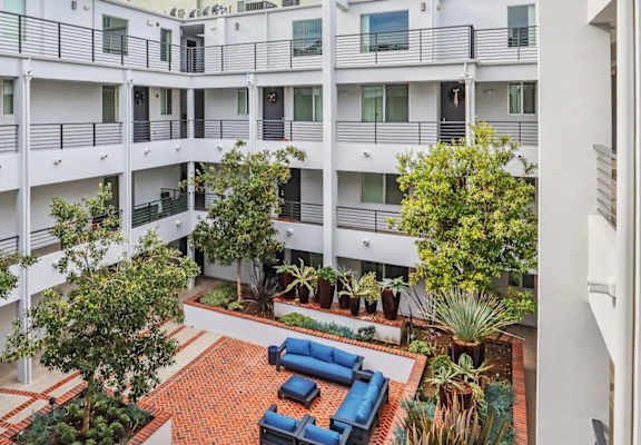 a large white apartment building with trees and a courtyard