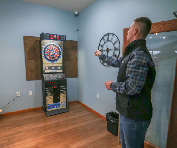 a man standing in a room playing a video game with a clock at Summit Ridge, Duluth