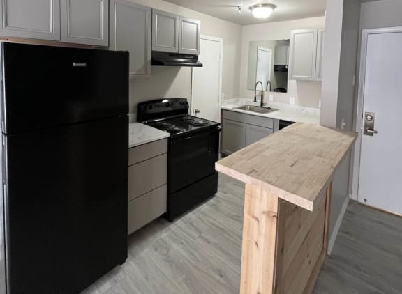 a kitchen with a black refrigerator freezer next to a stove top oven at The Lodge Apartments, Tulsa, 74129