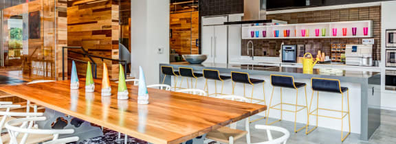 a long wooden table with chairs and a kitchen in the background