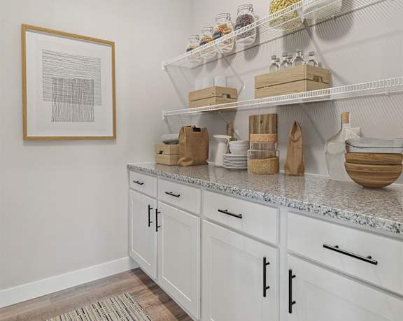a kitchen with white cabinets and baskets and baskets on shelves