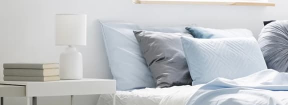 Bedroom with light blue bedding and decorative pillows at High Point Preserve Apartments, Texas, 78724