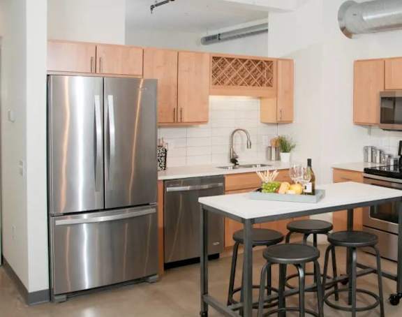 A kitchen with a refrigerator, microwave, oven, and sink.