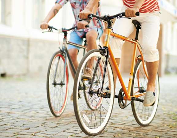 Two people riding bicycles on a cobblestone street.