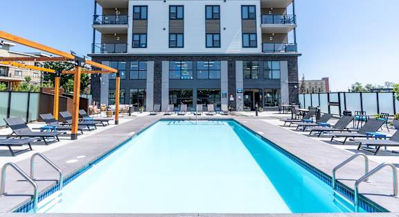 A large swimming pool in front of a multi-story apartment building.