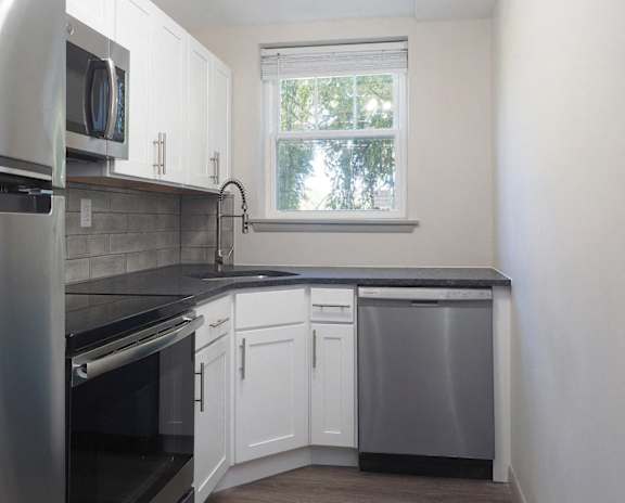 an empty kitchen with white cabinets and a black counter top  at Enclave West Hartford / Parc West, West Hartford, Connecticut