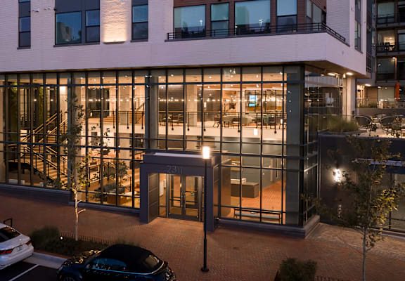 a large office building at night with cars parked in front of it