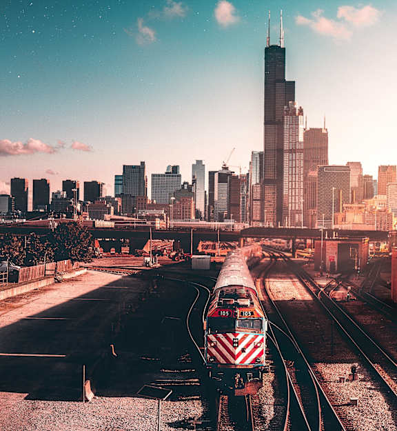 A train is on the tracks in front of a city skyline.