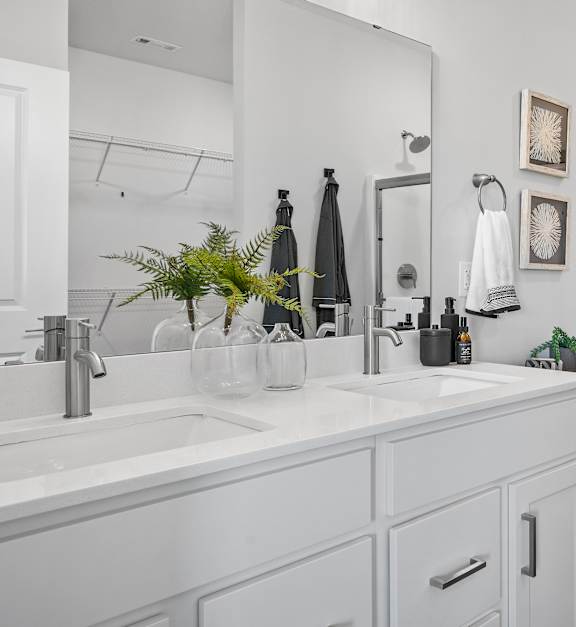 A white bathroom with a sink, mirror, toilet, and shower.