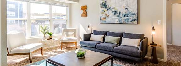 A living room with a grey couch, a coffee table, and a painting on the wall.