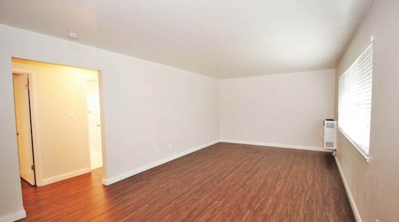 an empty living room with wood flooring and a window
