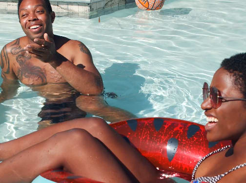 A man and a woman are sitting on an inflatable pool float.