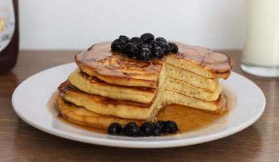 a stack of pancakes with blueberries on a white plate