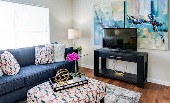 a living room with a blue couch and a tv on a stand in front of a window