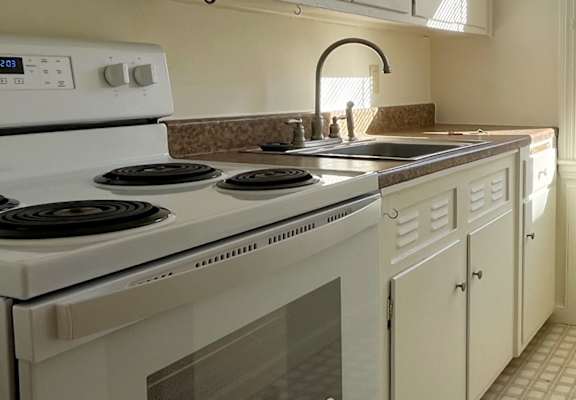 A kitchen with a white stove and white cabinets.