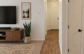A living room with a black fridge and a wooden floor.