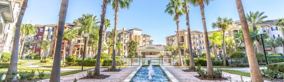 a fountain surrounded by palm trees in the middle of a resort