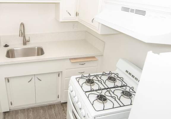 A white kitchen with a stove and sink.