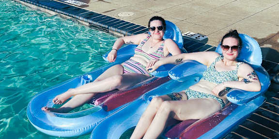 Two women are lounging on a pool float.