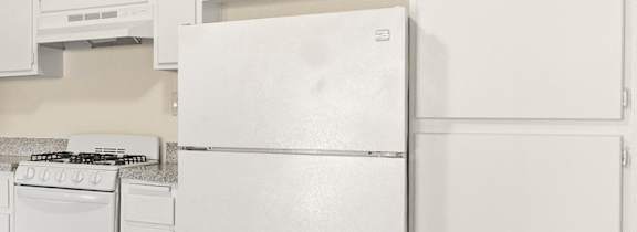 A kitchen with white appliances and brown flooring.