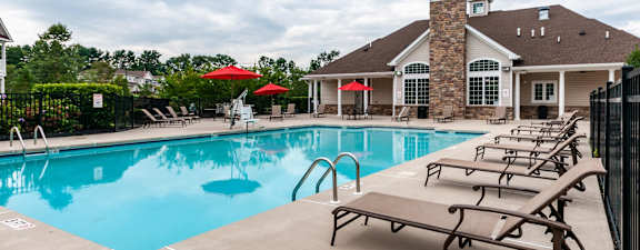 A pool with sun loungers and a building in the background.