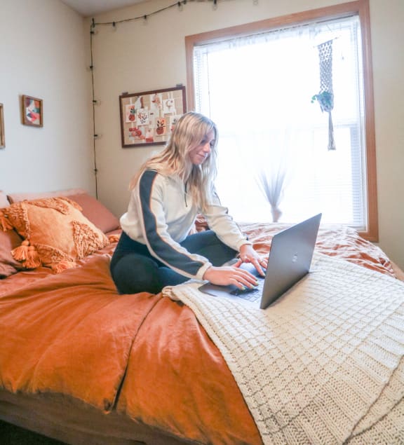 a woman sitting on a bed using a laptop computer at Summit Ridge, Duluth, MN