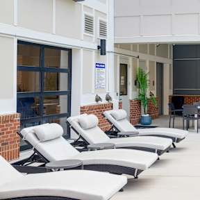 A pool area with lounge chairs and a table.