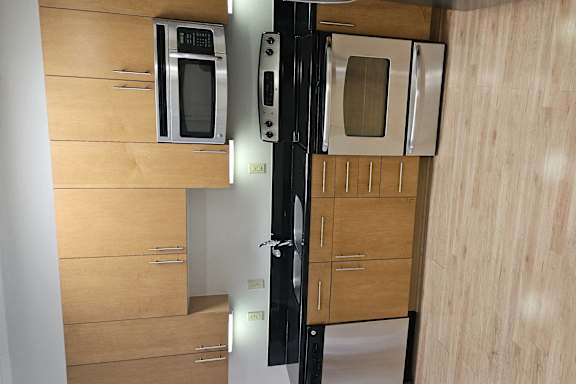 A kitchen with a black fridge and microwave above a wooden cabinet.
