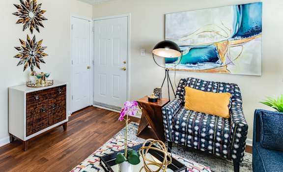 a living room with hardwood floors and a kitchen in the background