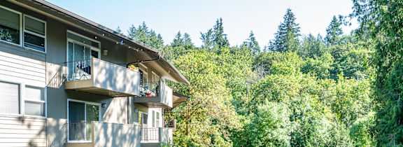 A building with a balcony is surrounded by greenery.