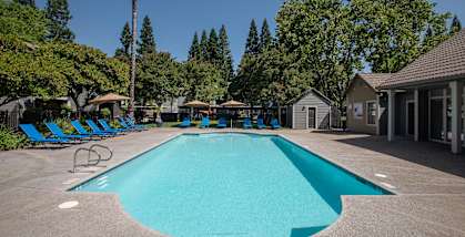 Bishops Court swimming pool and pool deck with umbrellas and blue lounge chairs and at Bishop's Court Apartments, California