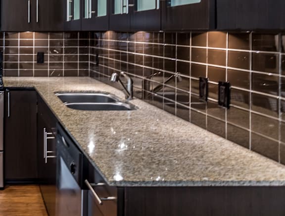 A kitchen with dark brown cabinets and a granite countertop.