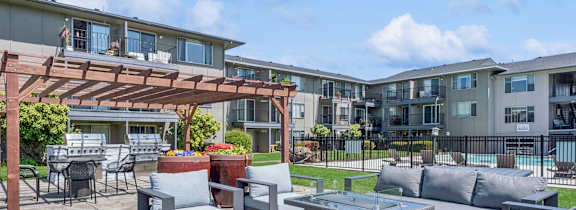 A patio area with grey furniture and a pool in the background.